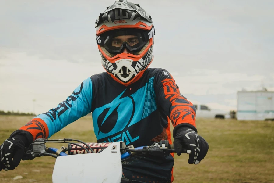 Man in vibrant protective gear on a motorcycle outdoors, displaying focus and energy