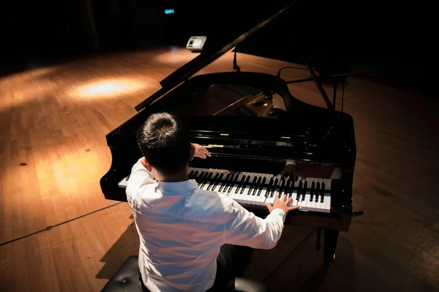 Man playing a grand piano on stage, creating musical harmony in a concert setting