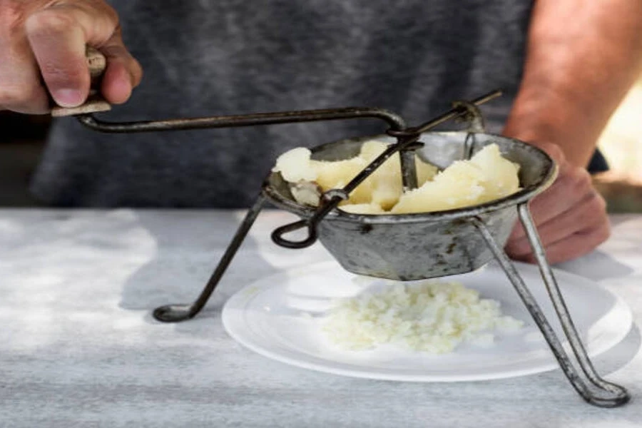 Man using rotary potato ricer on granite countertop