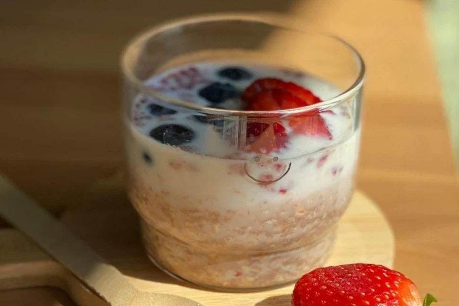 Mini bowl of berries and cream trifle on wooden table
