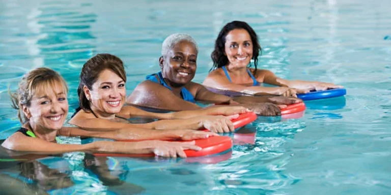 Multi-ethnic Group of Four Women in a Swimming Pool, Holding onto Kickboards
