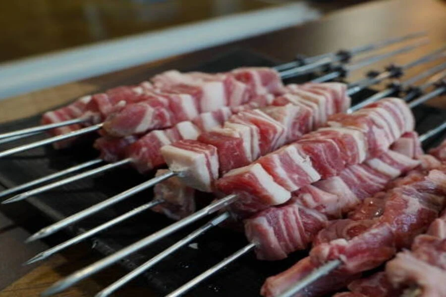 Narrow stainless steel skewers with chunks of meat impaled