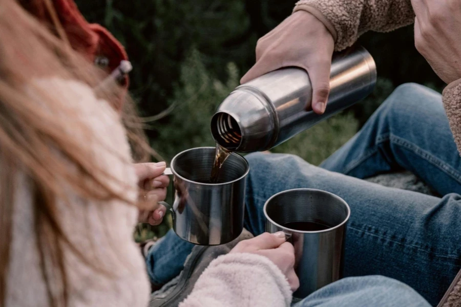 Person Pouring Hot Drink on Stainless Steel Mugs