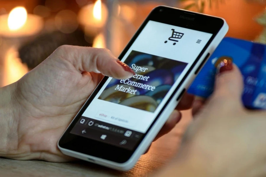 Person Using Black And White Smartphone and Holding Blue Card