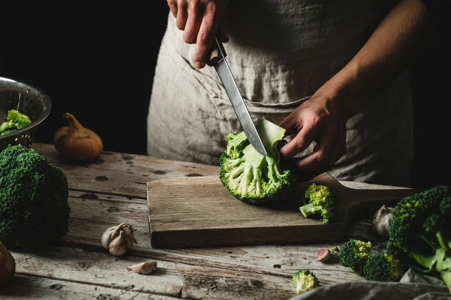 Person cutting broccoli with a chef’s knife
