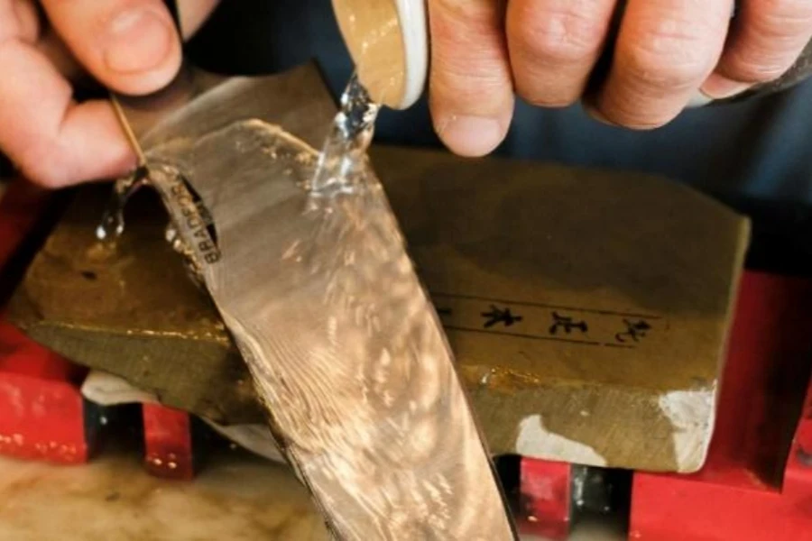 Person pouring water over knife on sharpening stone