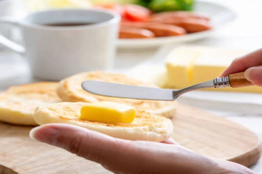Person using butter knife to spread butter on bread