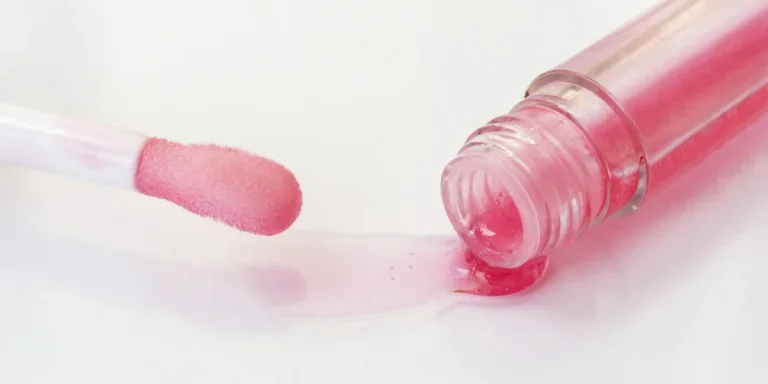 Pink lip oil flowing out of a bottle