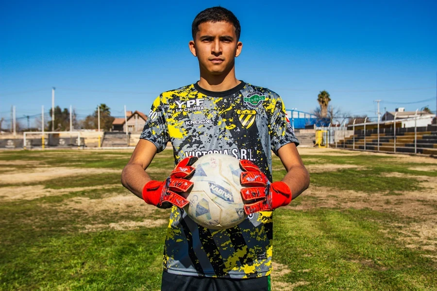 Portrait of a young soccer player holding a ball on a sunny outdoor field