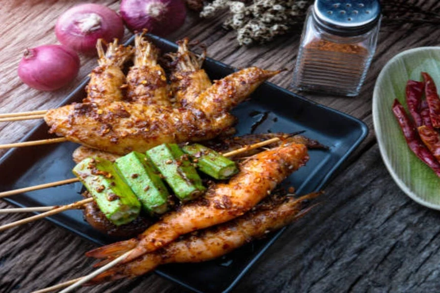 Seafood served on bamboo sticks with red onions and cumin