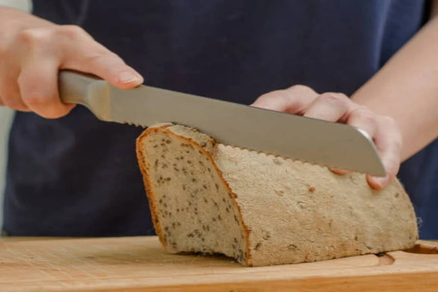 Seeded loaf of bread with hand holding it to cut