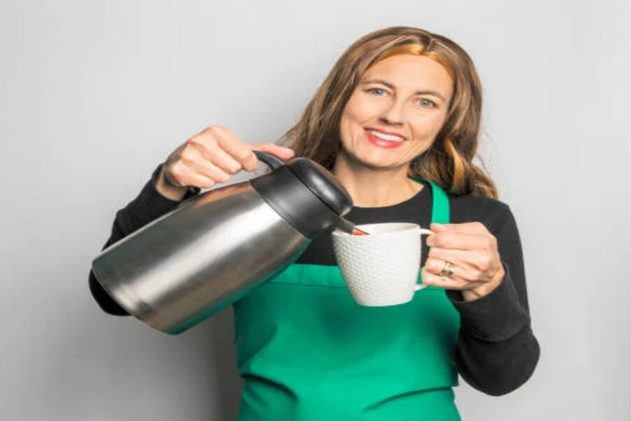 Server pouring favorite coffee from brewer into thermo mug