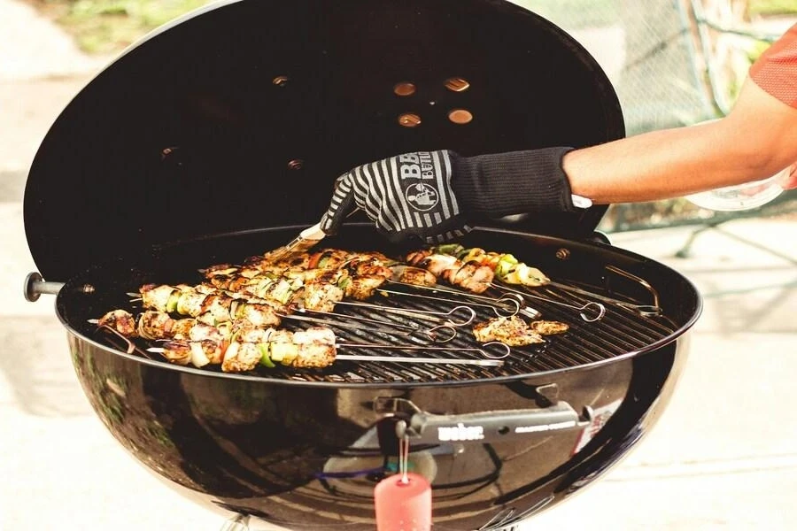 Small outdoor barbecue with chicken skewers cooking on grill