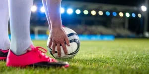 Soccer Player Putting Sports Ball on Field Grass