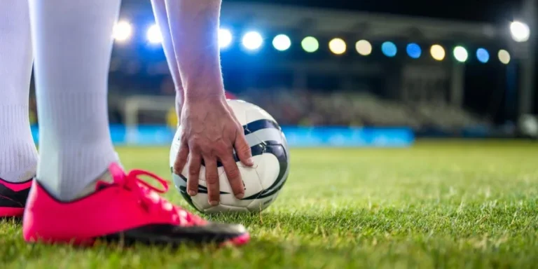 Soccer Player Putting Sports Ball on Field Grass