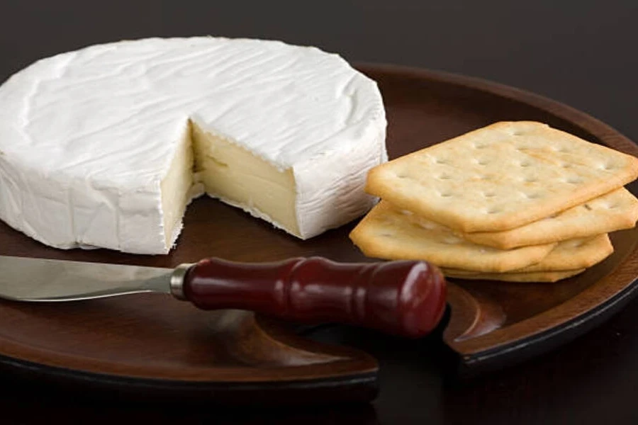 Spreader knife with wood handle next to cheese and crackers