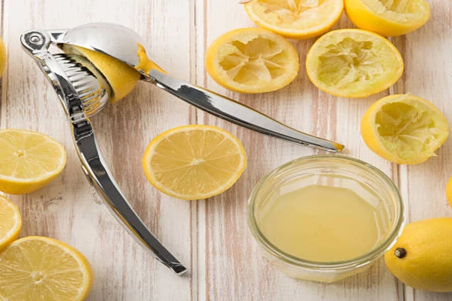Stainless steel handheld lemon squeezer with lemon juice in bowl