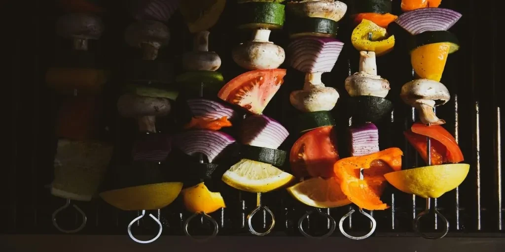 Stainless steel skewers with roasted vegetables on barbecue
