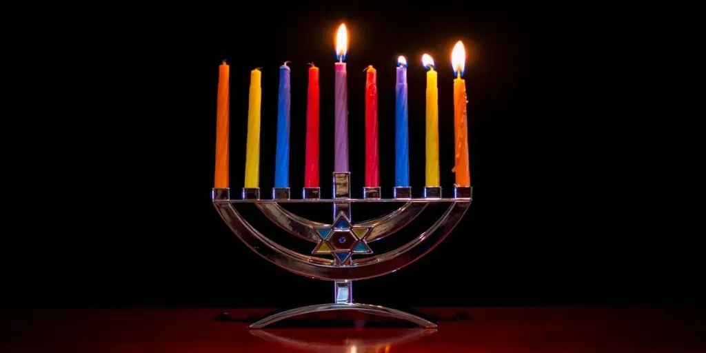 Standard menorah candles in different colors lit up at night