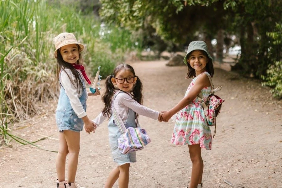 Three kids in fashionable summer clothing holding hands