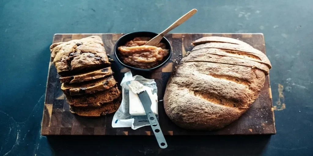 Two loaves of fresh bread next to butter on knife