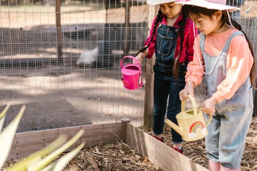 Two young girls on sun hats watering a plant