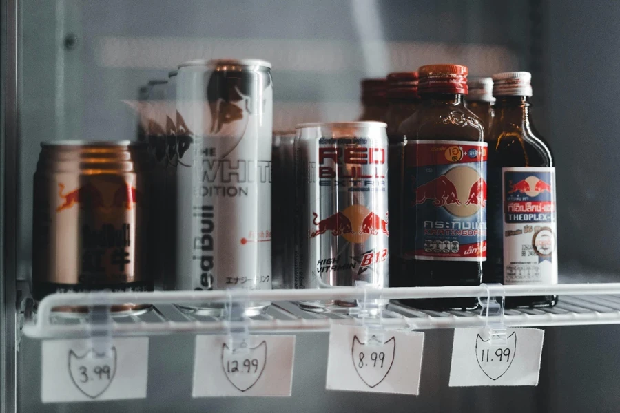 Variety of energy drinks displayed with prices on a refrigerator shelf
