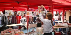 Vibrant marketplace with red tents, shoppers, and colorful goods on display