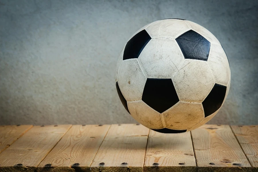 Vintage soccer ball resting on wooden planks against a textured background, symbolizing sports tradition
