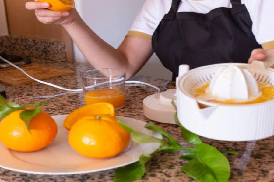 White plastic electric citrus juicer juicing fresh oranges