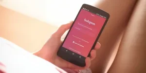 Une femme tenant un téléphone avec la page d'inscription d'Instagram