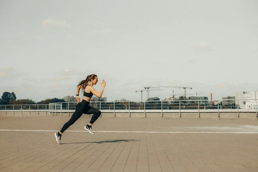 Woman sprinting on a rooftop in athletic wear during the day