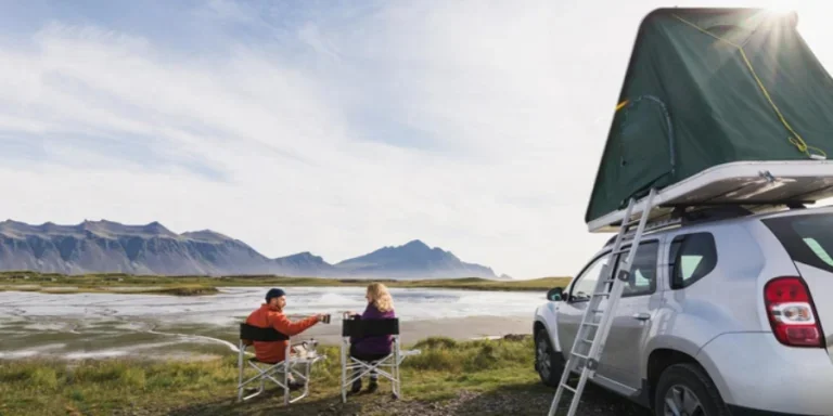 Young Couple Sitting Beside Car Rooftop Tent