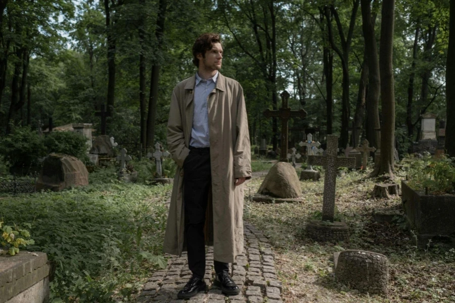 A Man in a Trench Coat Standing in an Old Cemetery