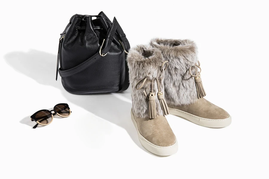 A black bucket bag kept with boots and sunglasses