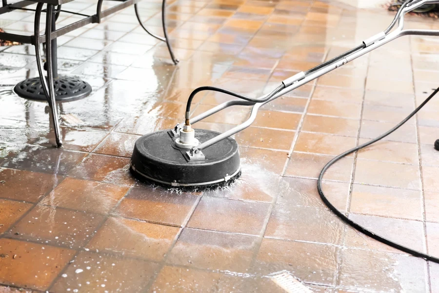 A black corded electric scrubber cleaning tiles