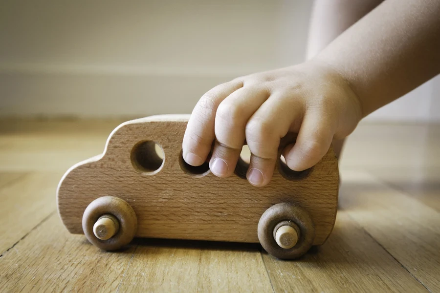 A child playing with a wooden toy bus