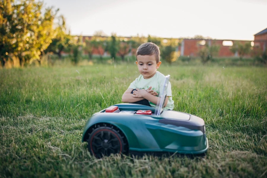 A little boy watching the AI lawnmower cut grass