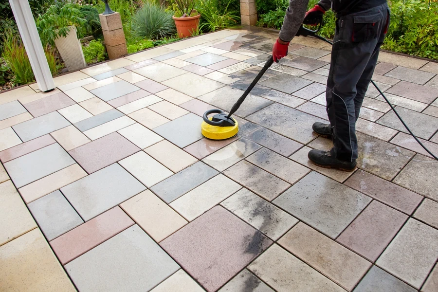 A man cleaning with a patio with an electric spin scrubber