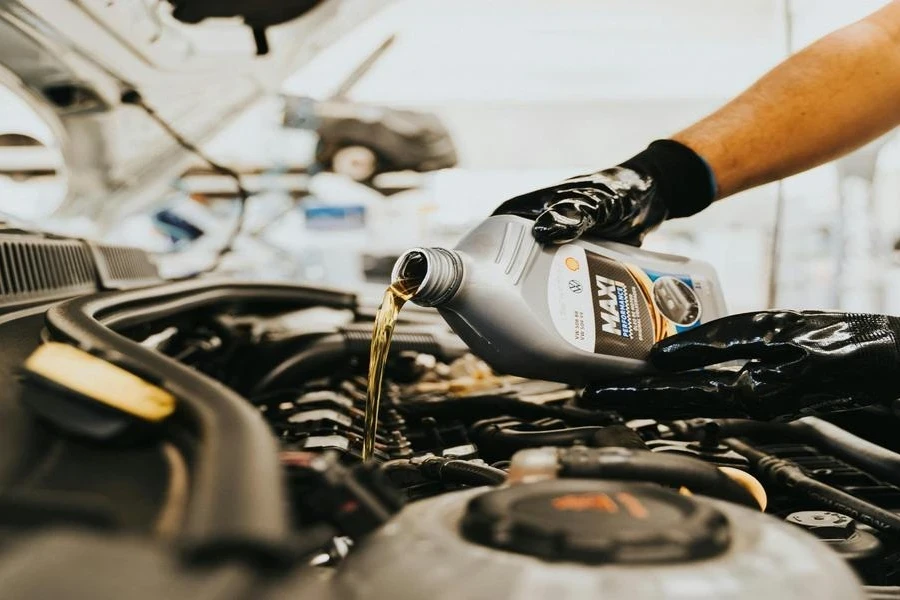 A person adding oil into a car engine