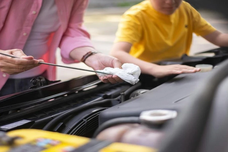 A person checking the oil level in a car engine