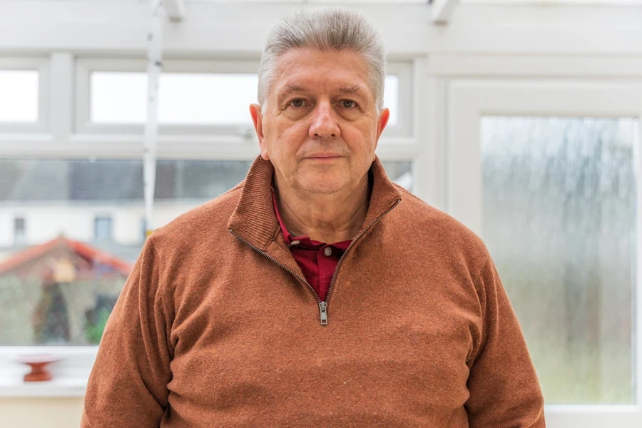 A senior person wearing brown zipped sweater