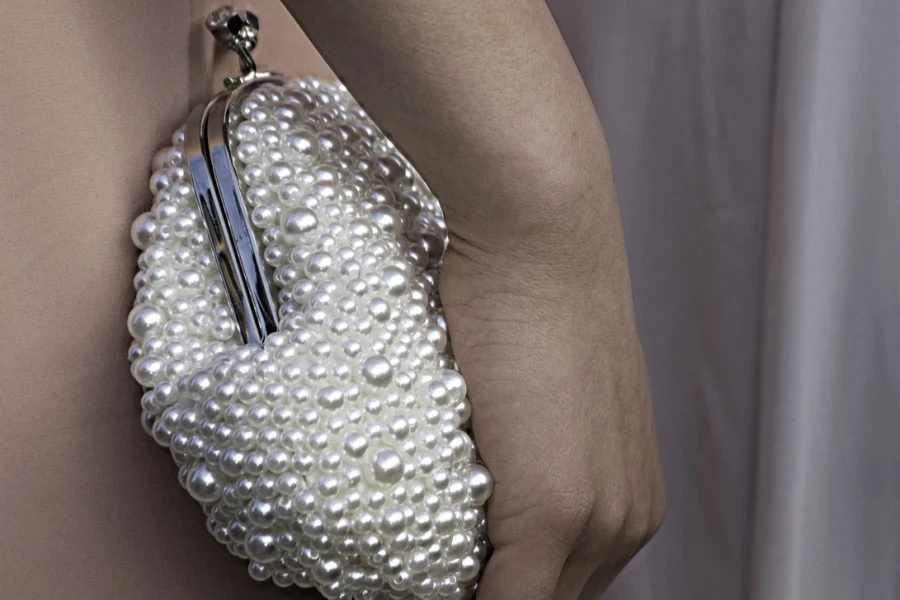 A woman holding a beaded clutch purse
