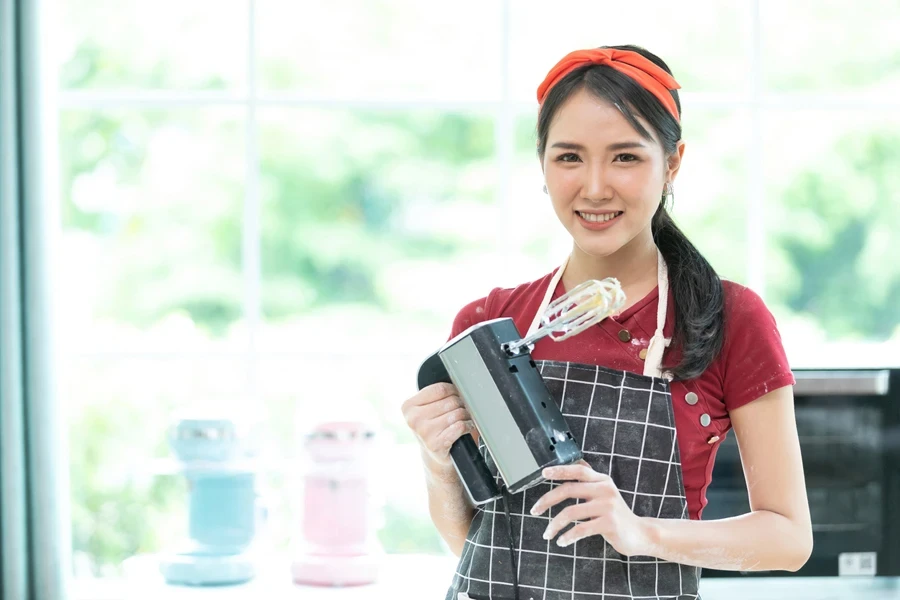 A woman holding an electric whisk