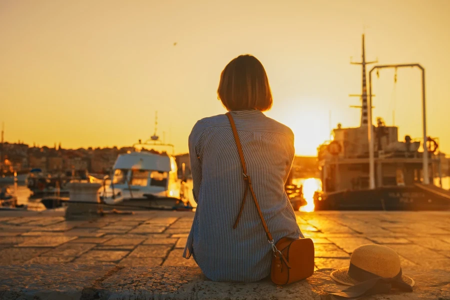A woman watching sunset with a crossbody bag across her shoulder