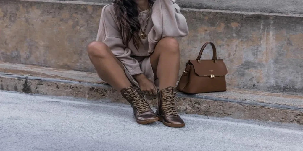 A woman wearing brown boots with a brown bag beside her