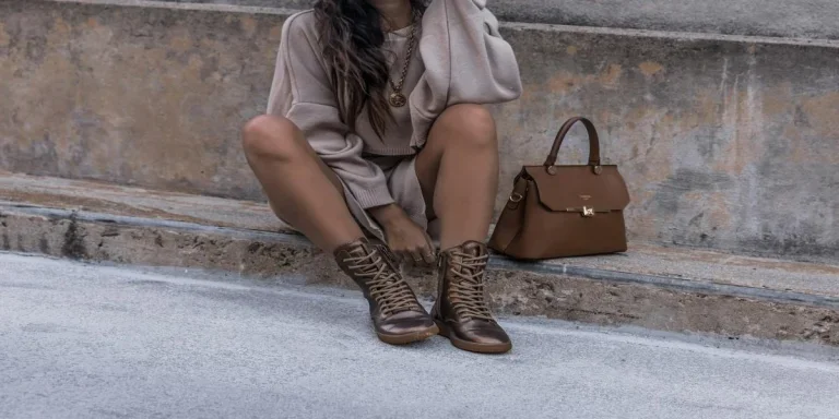 A woman wearing brown boots with a brown bag beside her