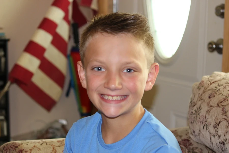A young boy smiling with a classic crew cut