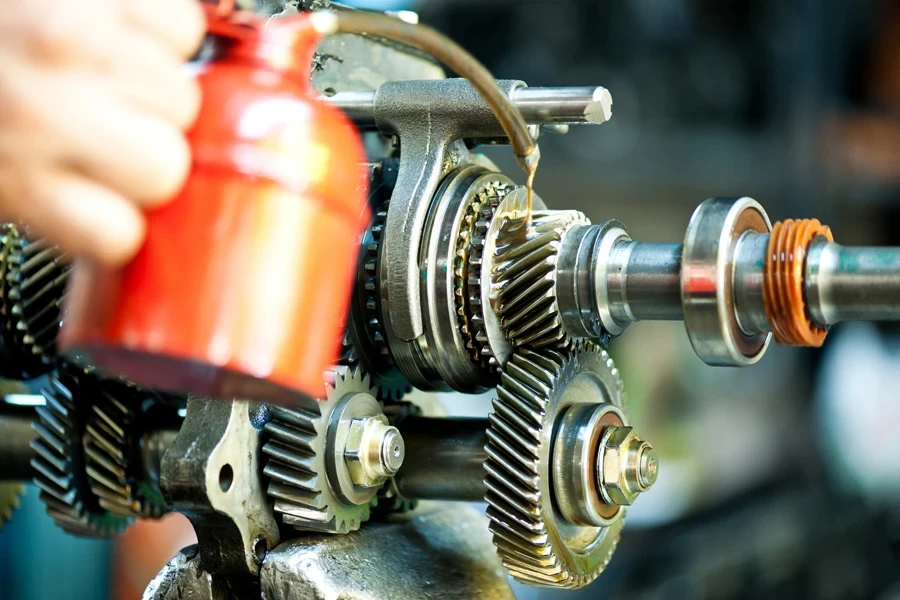 Auto mechanic adding transmission fluid on gears