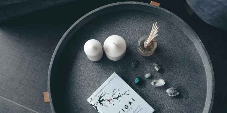 Candles, stones, and a book arranged on a ceramic tray